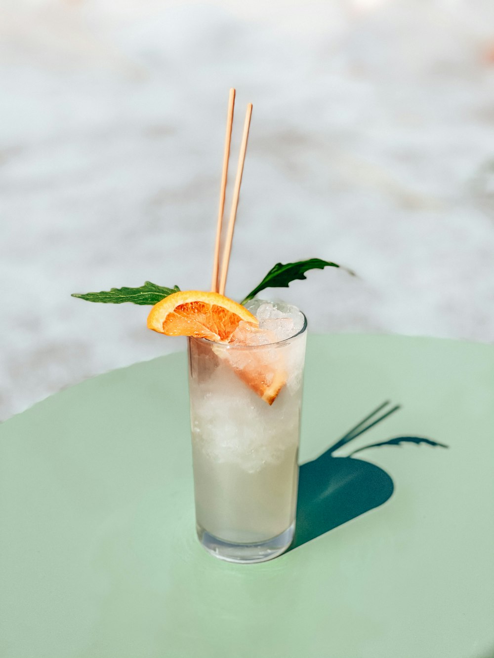 clear drinking glass with white liquid and orange slice on green leaf