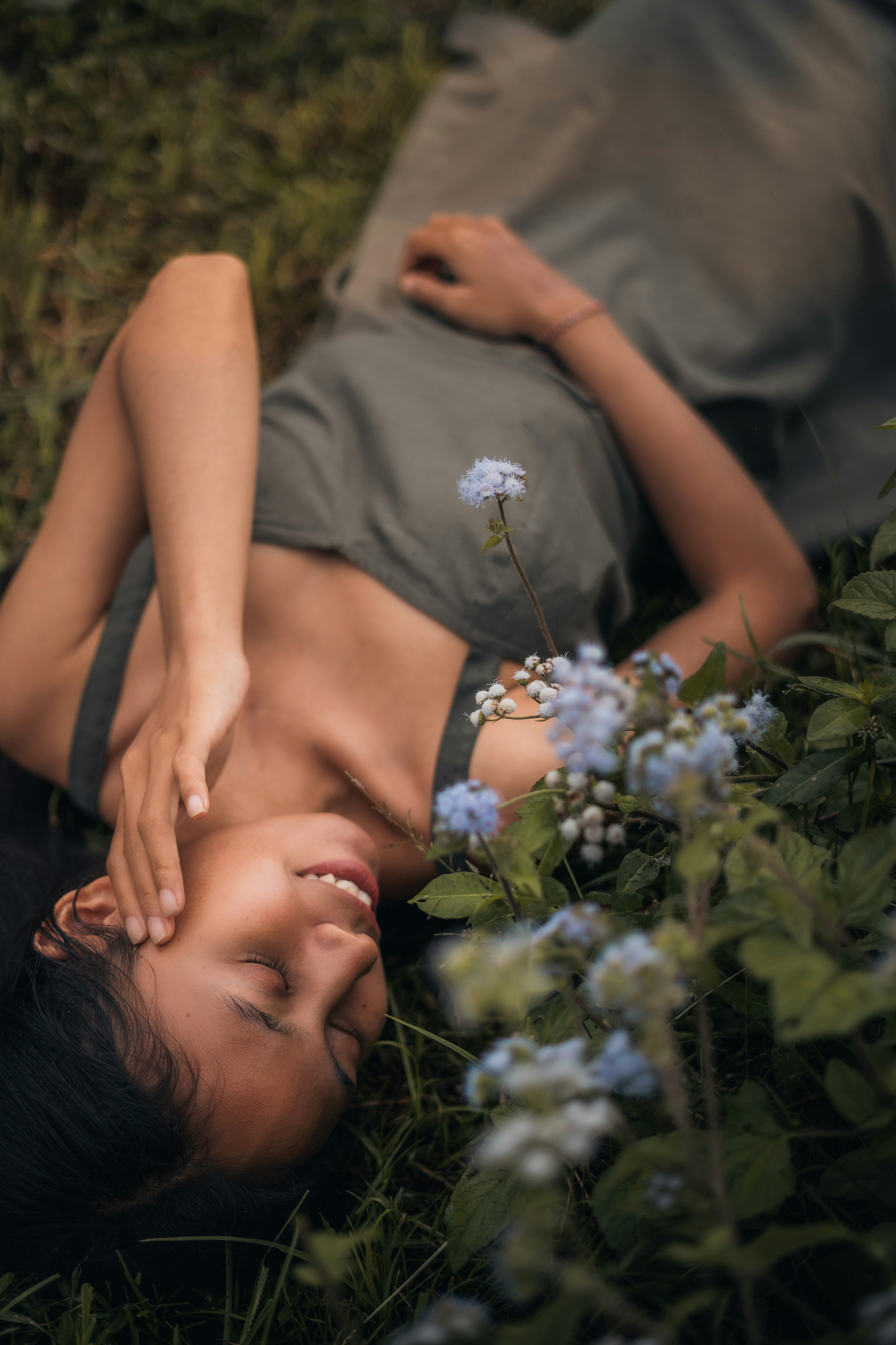 woman in gray shirt lying on green grass field