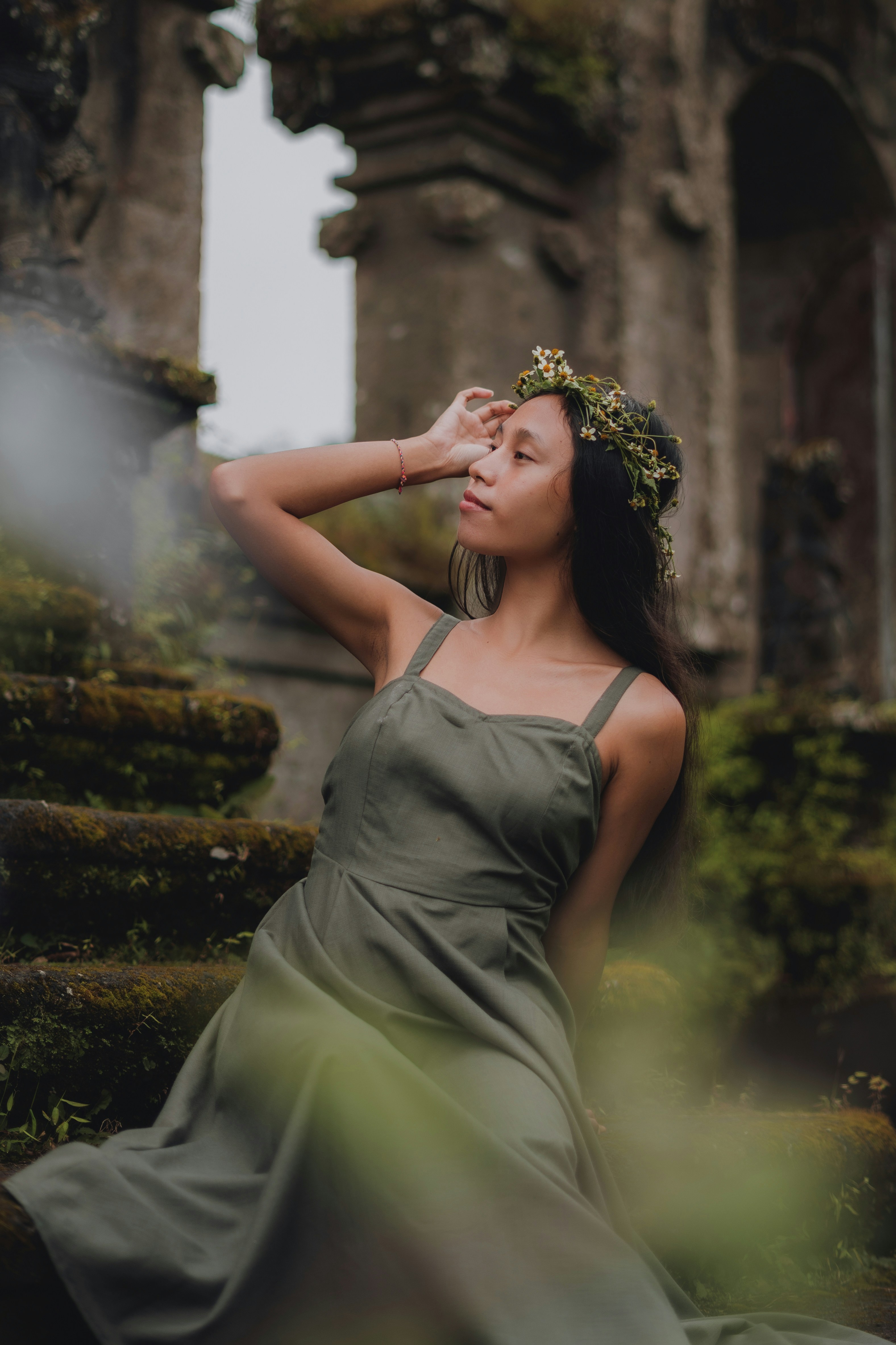 woman in green sleeveless dress holding her face