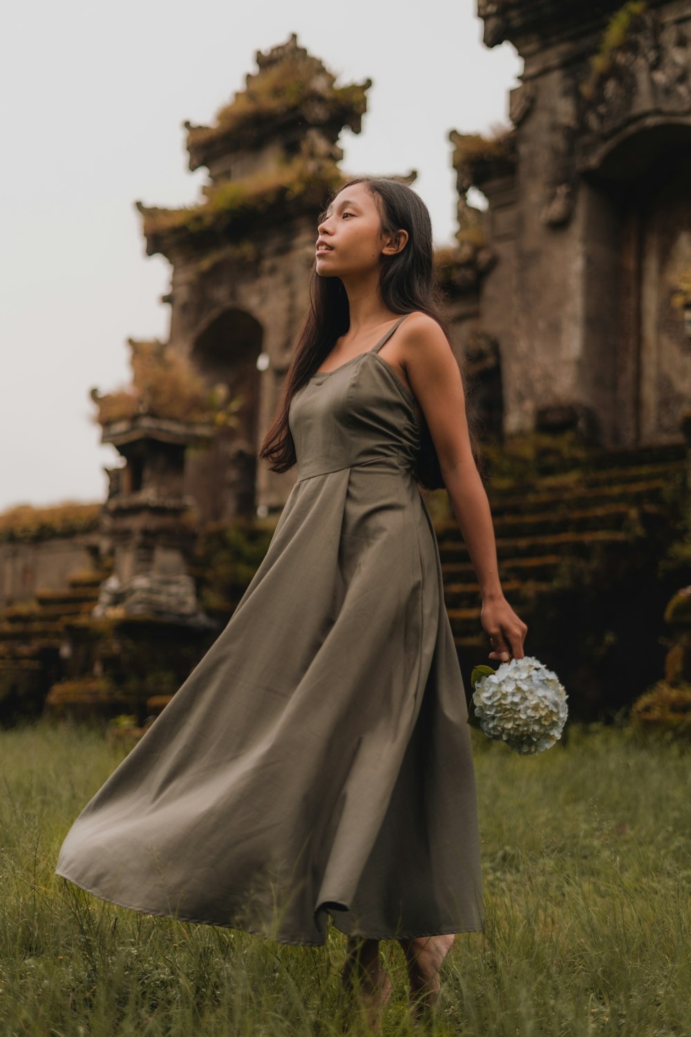 woman in gray dress sitting on green grass field during daytime