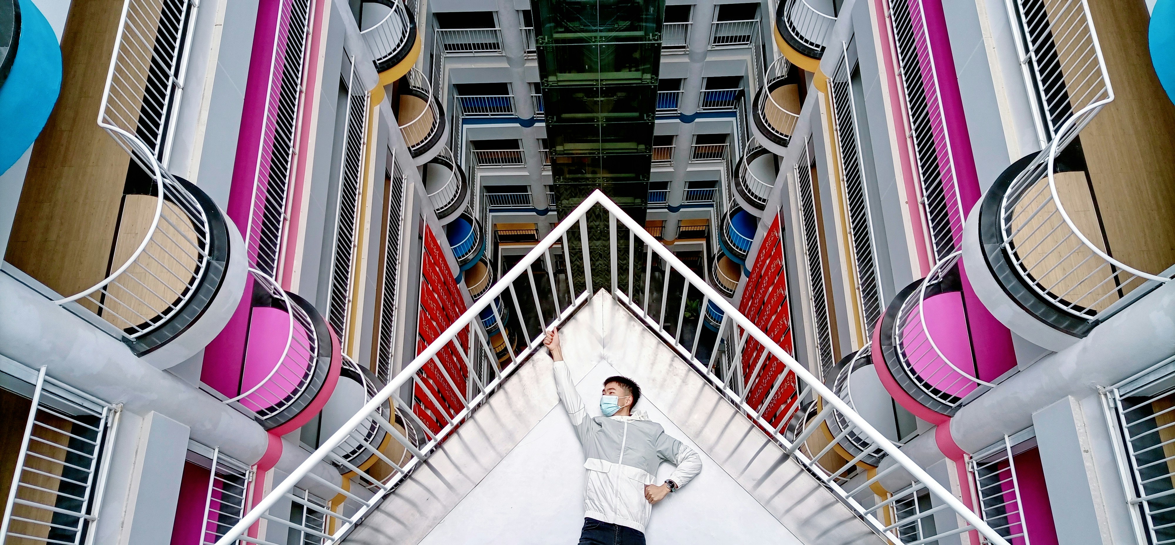 man in white long sleeve shirt and blue denim jeans standing on white staircase