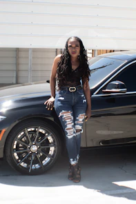 woman in blue denim jeans standing beside black car