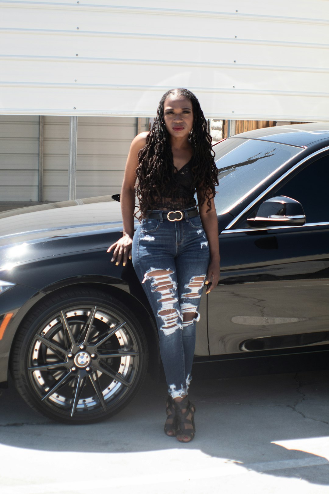 woman in blue denim jeans standing beside black car