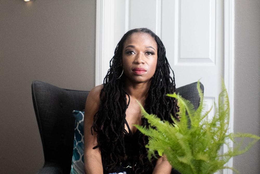 woman in blue sleeveless dress sitting on black couch