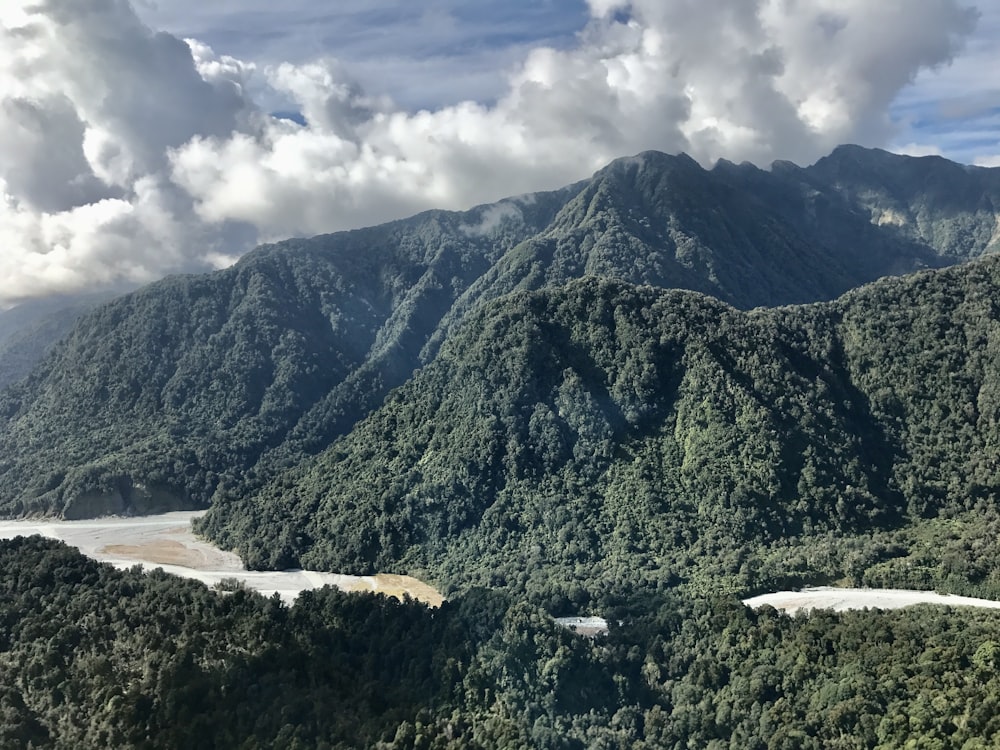 green mountain near body of water under cloudy sky during daytime