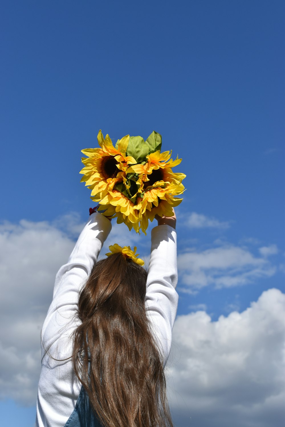 woman in white long sleeve shirt holding yellow flower