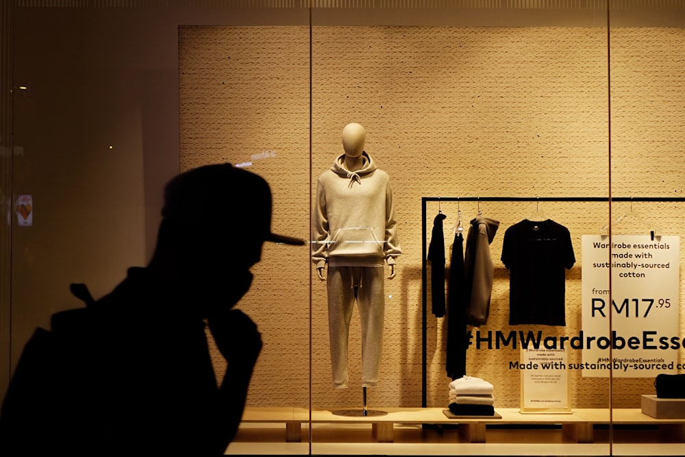 man in black hoodie standing in front of black and white clothes