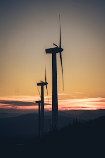 A wind farm with turbines spinning against a sunset backdrop.