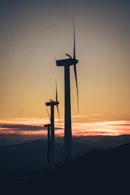 A wind farm with turbines spinning against a sunset backdrop.
