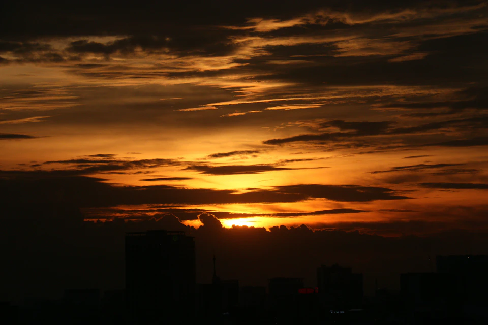 City skyline at sunset with warm glow and golden hues behind buildings