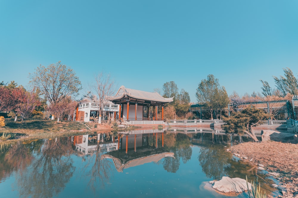 brown and white house near body of water under blue sky during daytime