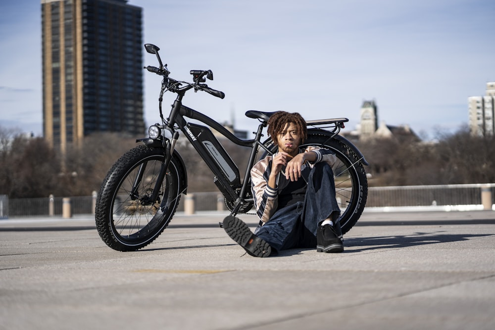 woman in black jacket and blue denim jeans sitting on road bike during daytime