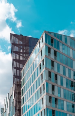 Geometric modern buildings with reflective glass facades under a bright blue sky, highlighting architectural design and urban development.