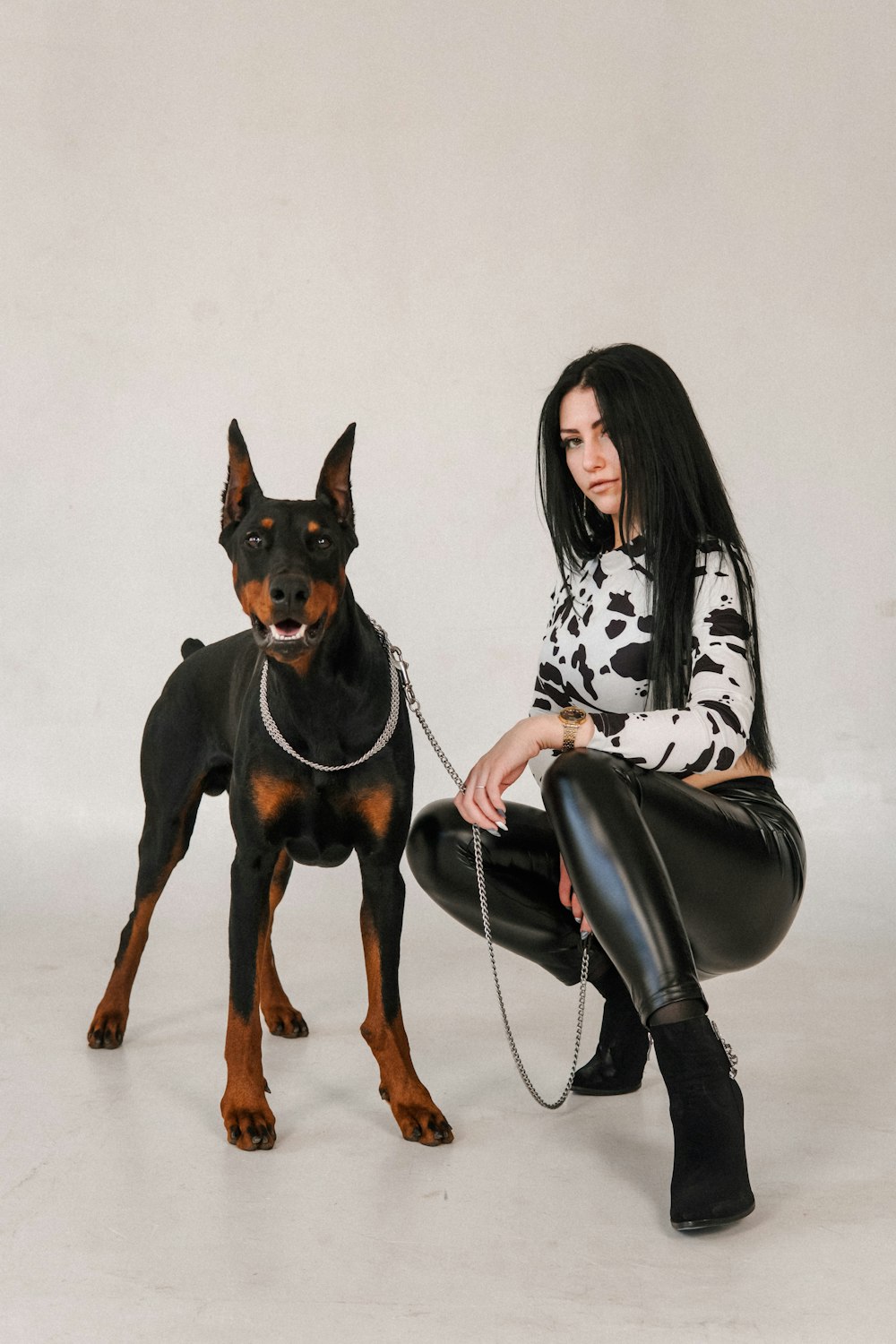 woman in black and white long sleeve shirt sitting beside black and brown short coated dog