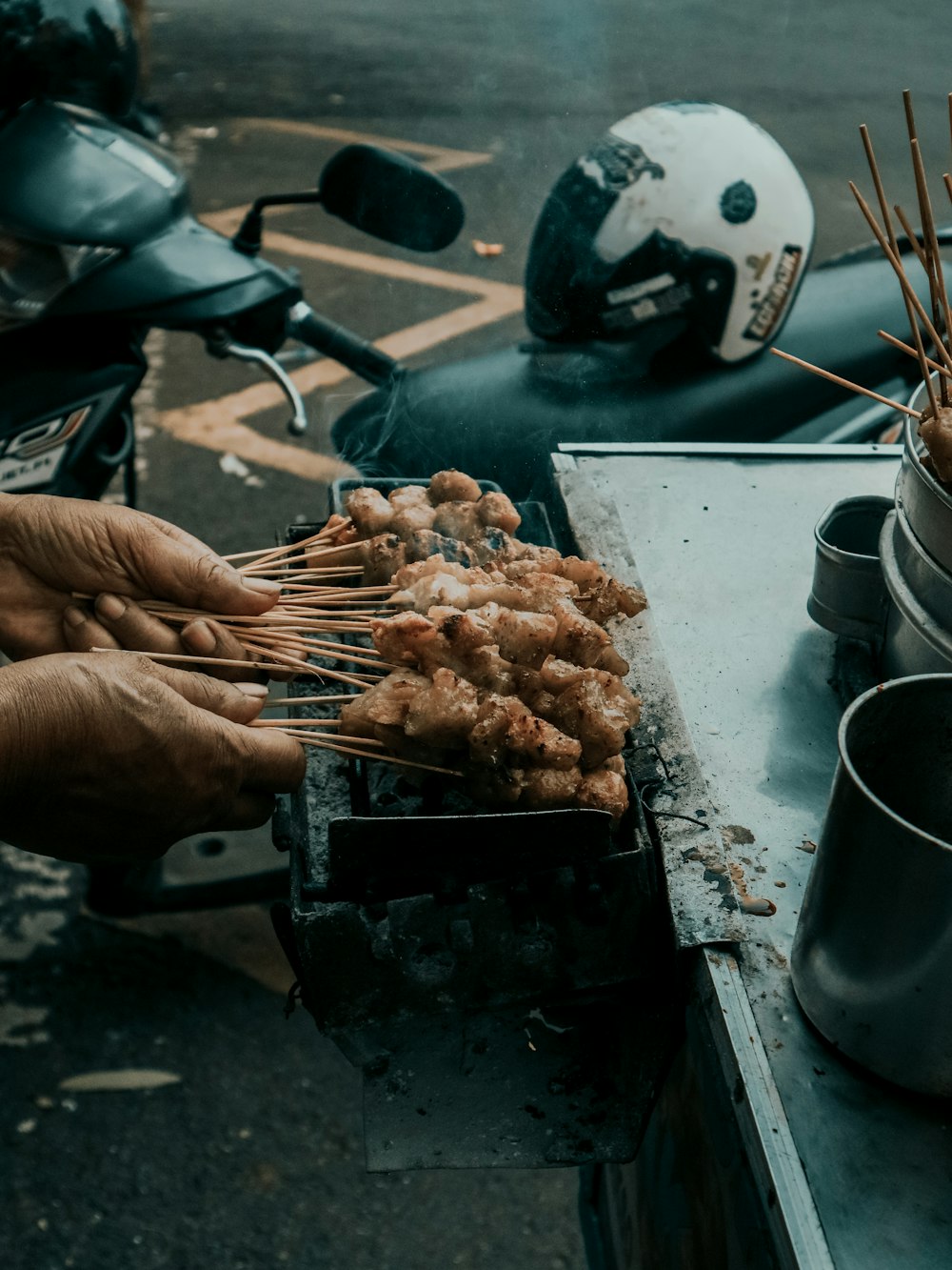 person holding grilled meat on charcoal grill