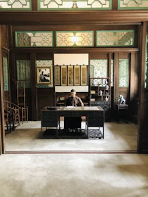 A focused student studying with a laptop, surrounded by Chinese cultural elements in a modern setting.