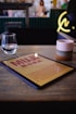 red book beside clear drinking glass on brown wooden table
