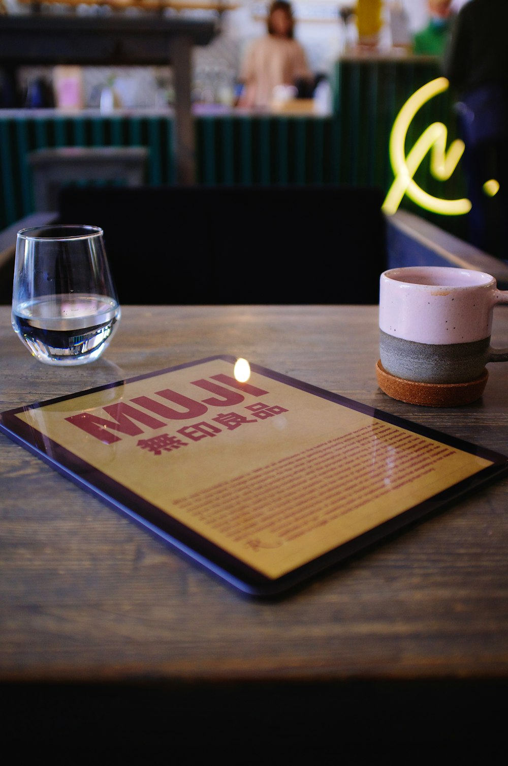 Livre rouge à côté d’un verre à boire transparent sur une table en bois brun