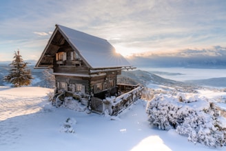Cozy mountain cabin with snowy Bariloche landscape in the background during sunset.