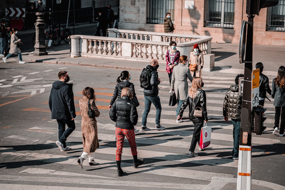 pessoas andando na faixa de pedestres durante o dia