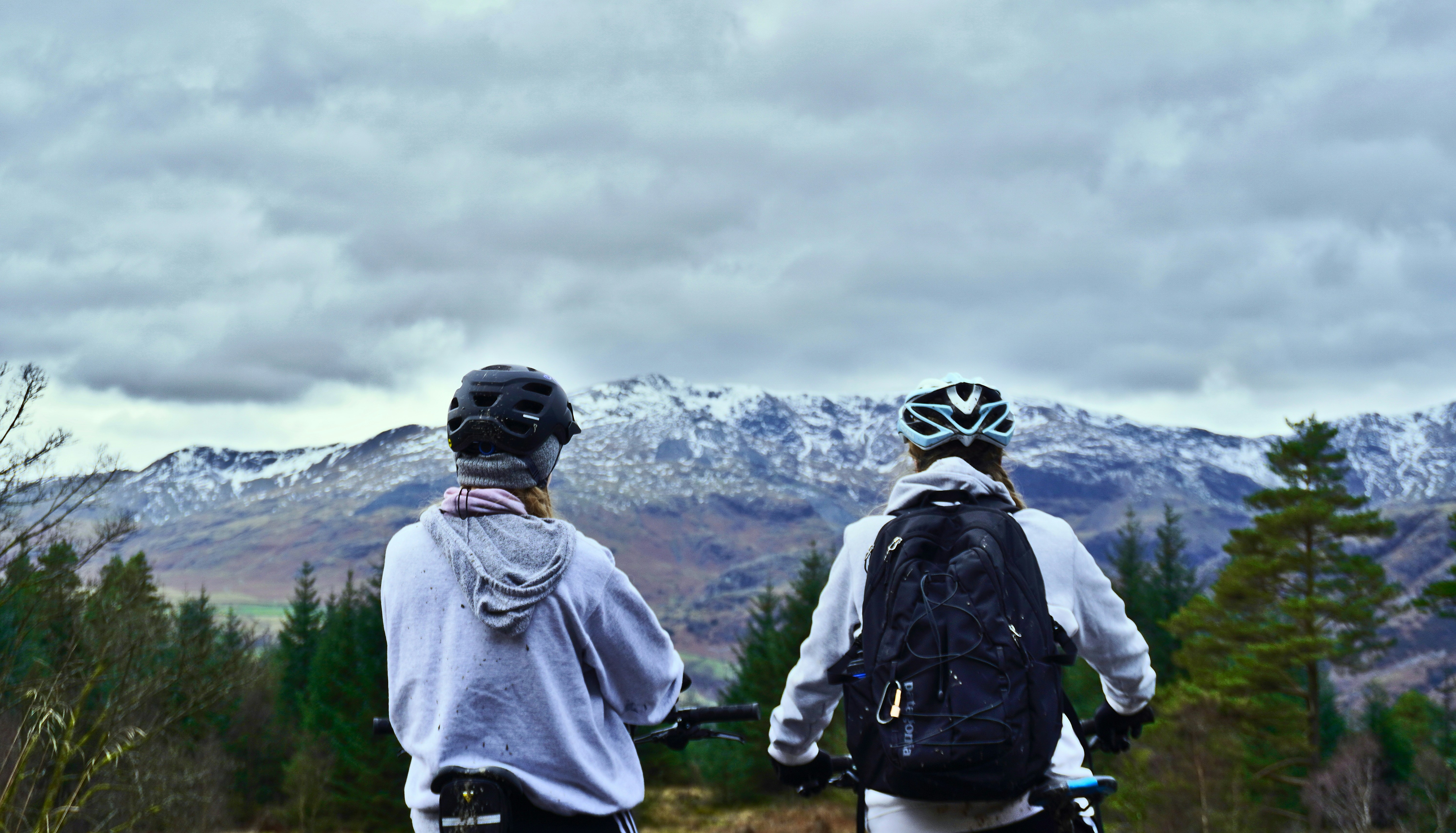 2 person wearing backpacks and backpacks standing on green grass field during daytime