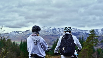 2 person wearing backpacks and backpacks standing on green grass field during daytime