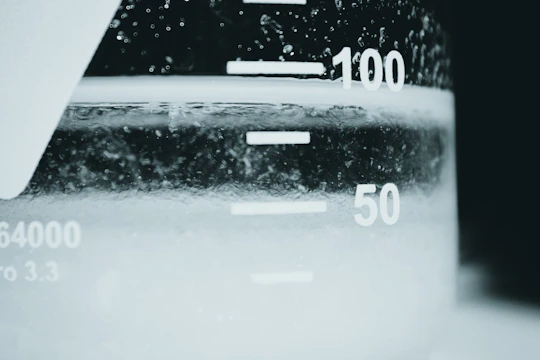 Close-up view of a student carefully mixing chemicals in a clear beaker at home.