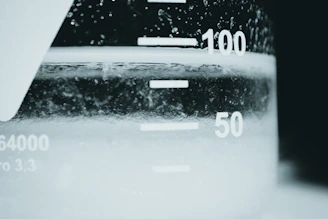 Close-up of a scientist carefully measuring a blue liquid in a laboratory glass beaker.