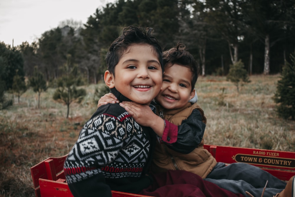 boy in black and white tribal print jacket smiling beside boy in red jacket