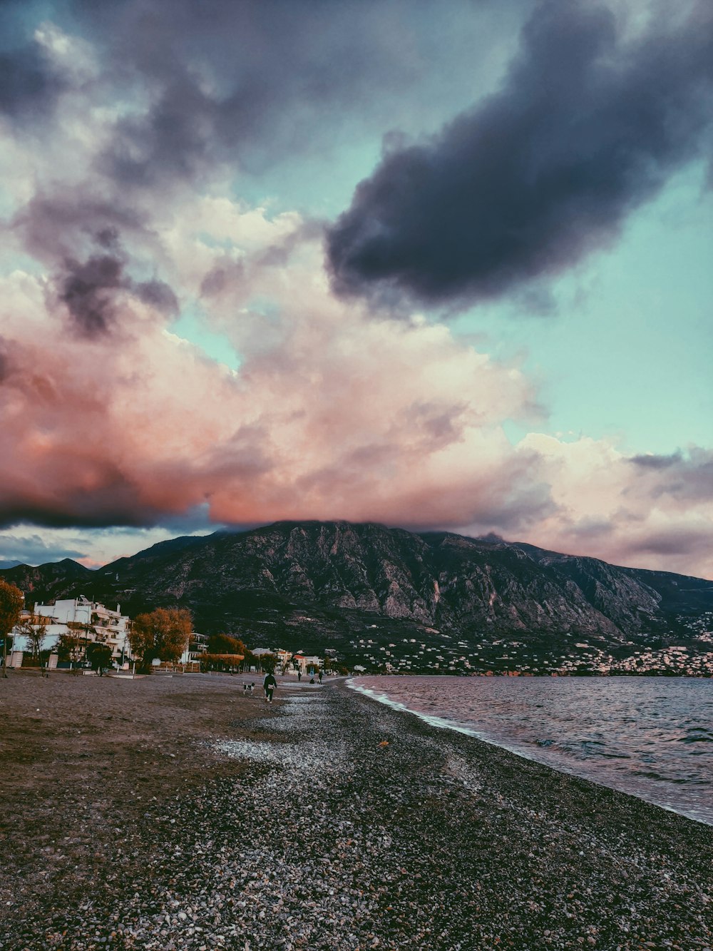 Maisons blanches et brunes près de la montagne sous les nuages blancs pendant la journée