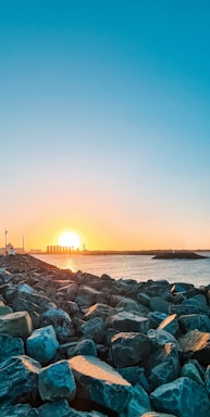 A calm coastal scene with engineers discussing plans by the shoreline at sunset.
