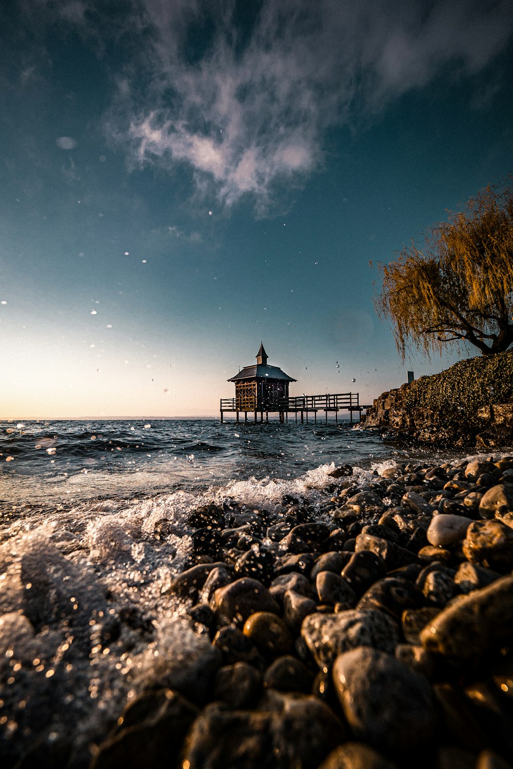 brown wooden house on rocky shore during night time