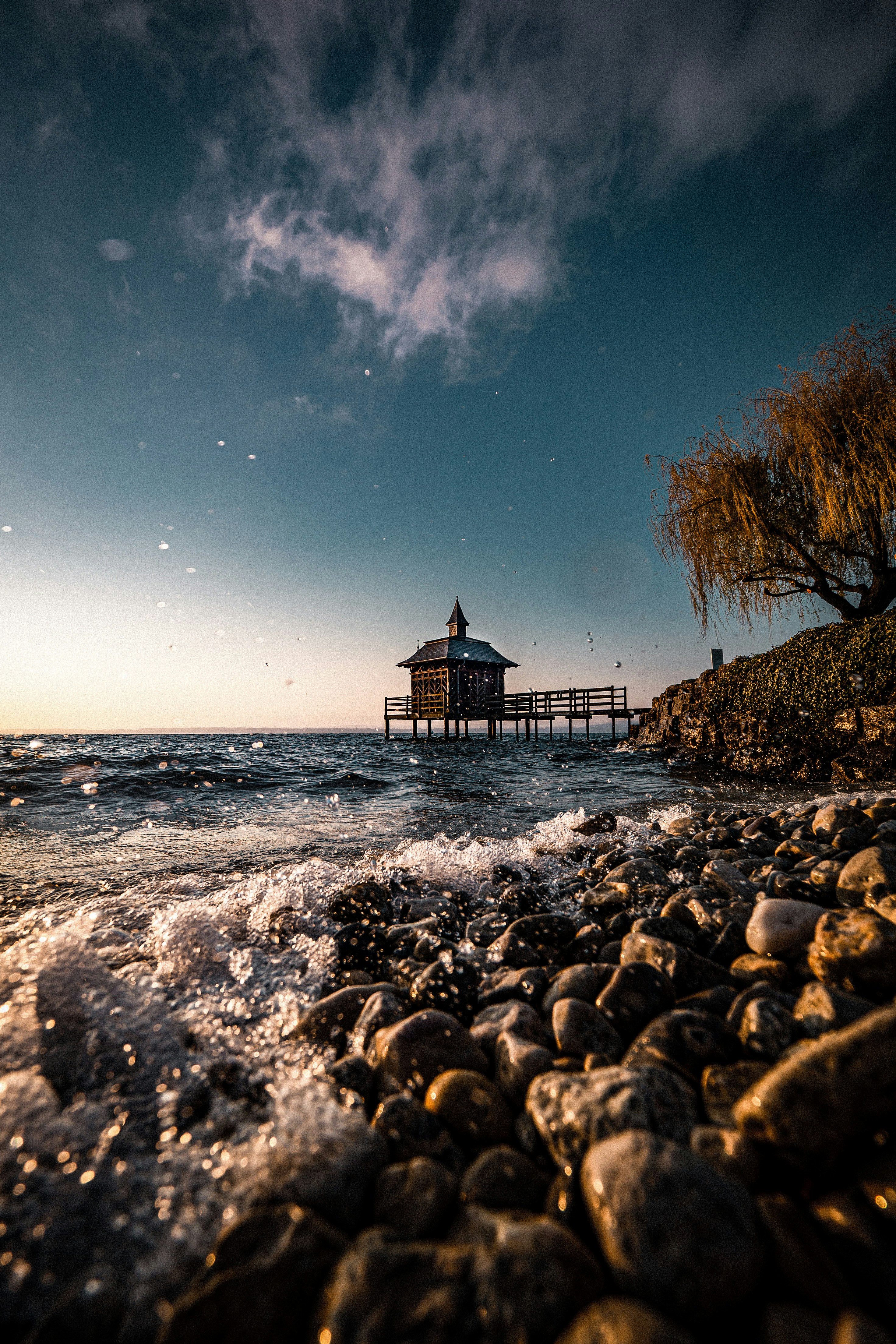brown wooden house on rocky shore during night time
