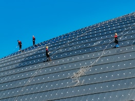 Male helpers in blue uniforms assisting with industrial site maintenance under clear skies.