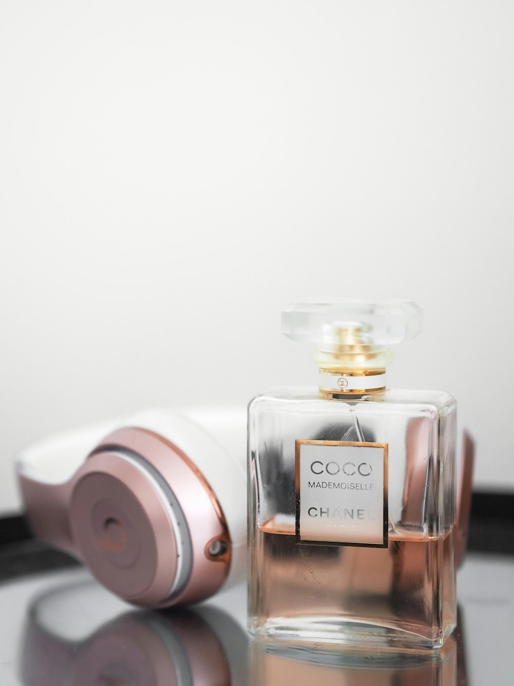 chanel perfume bottle beside pink beats by dr dre headphones