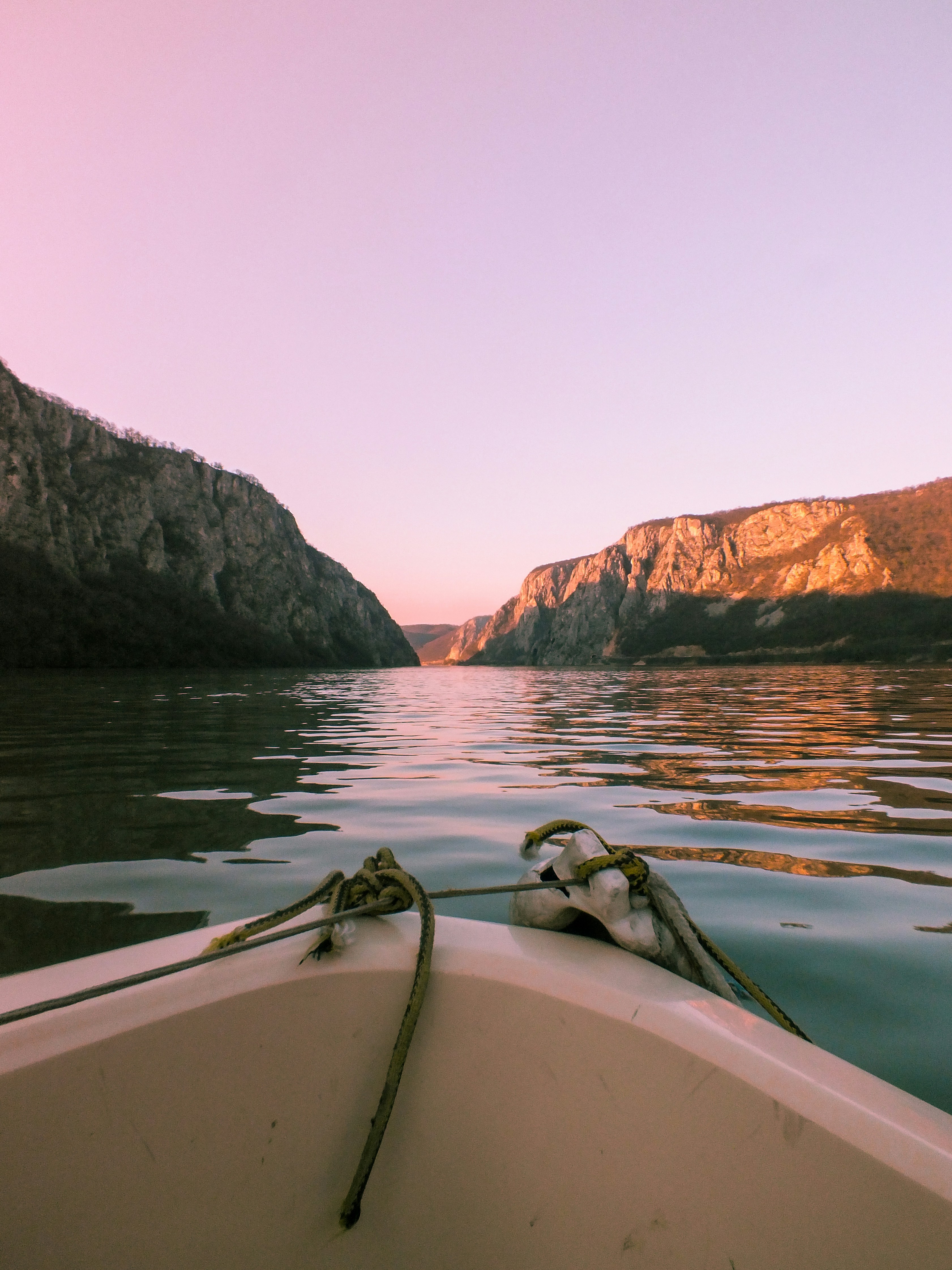 white boat on water near brown rocky mountain during daytime