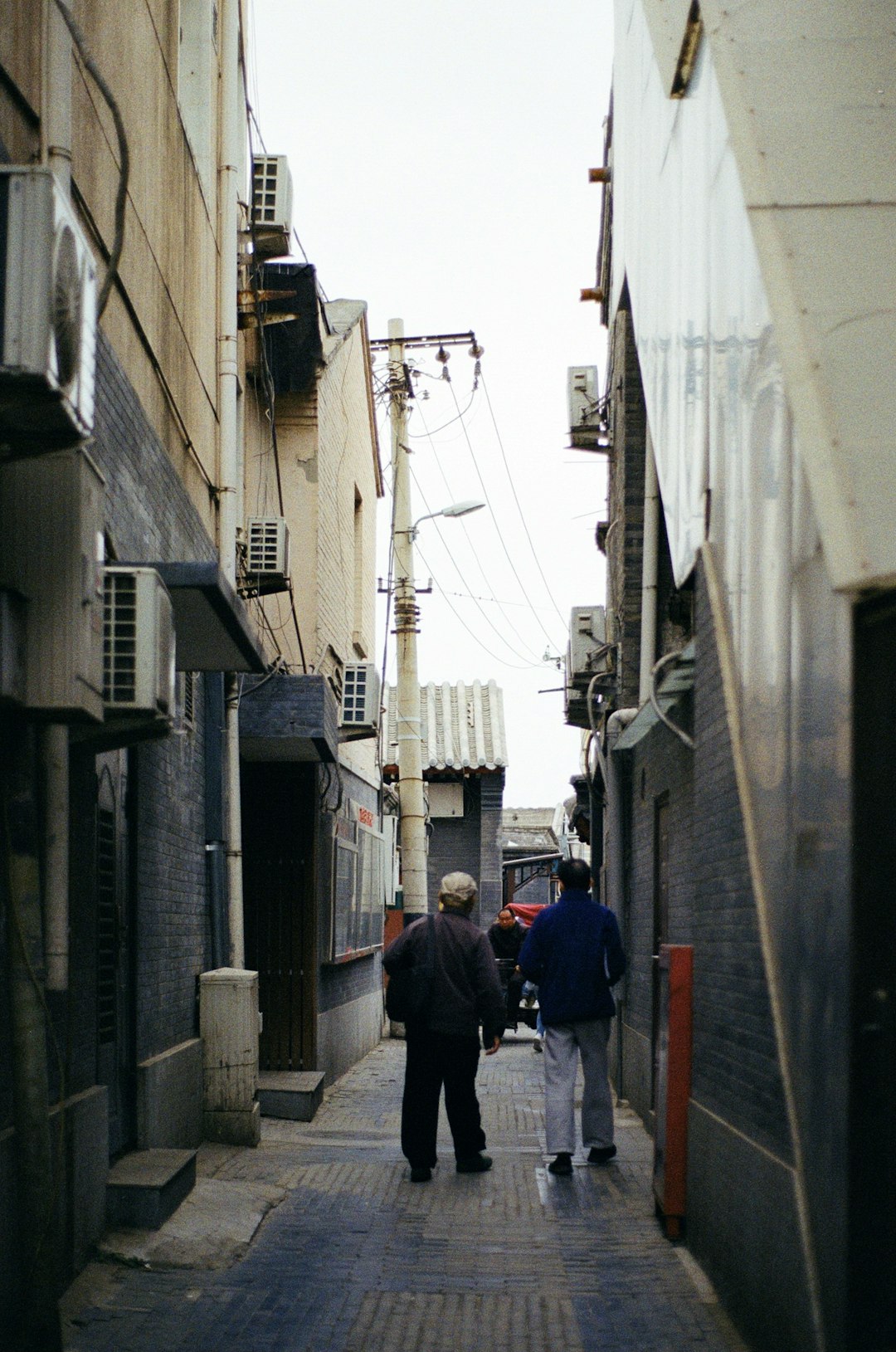 man in blue jacket walking on sidewalk during daytime