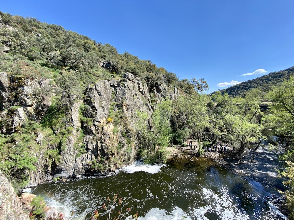 grüner und grauer Berg am Fluss unter blauem Himmel tagsüber