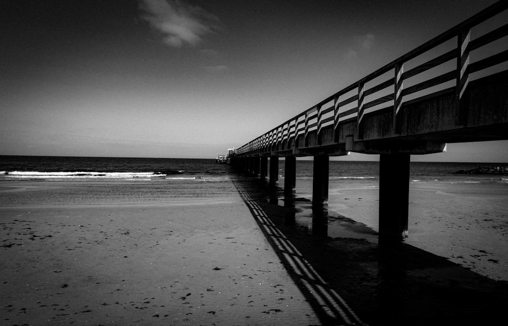 grayscale photo of wooden dock on beach