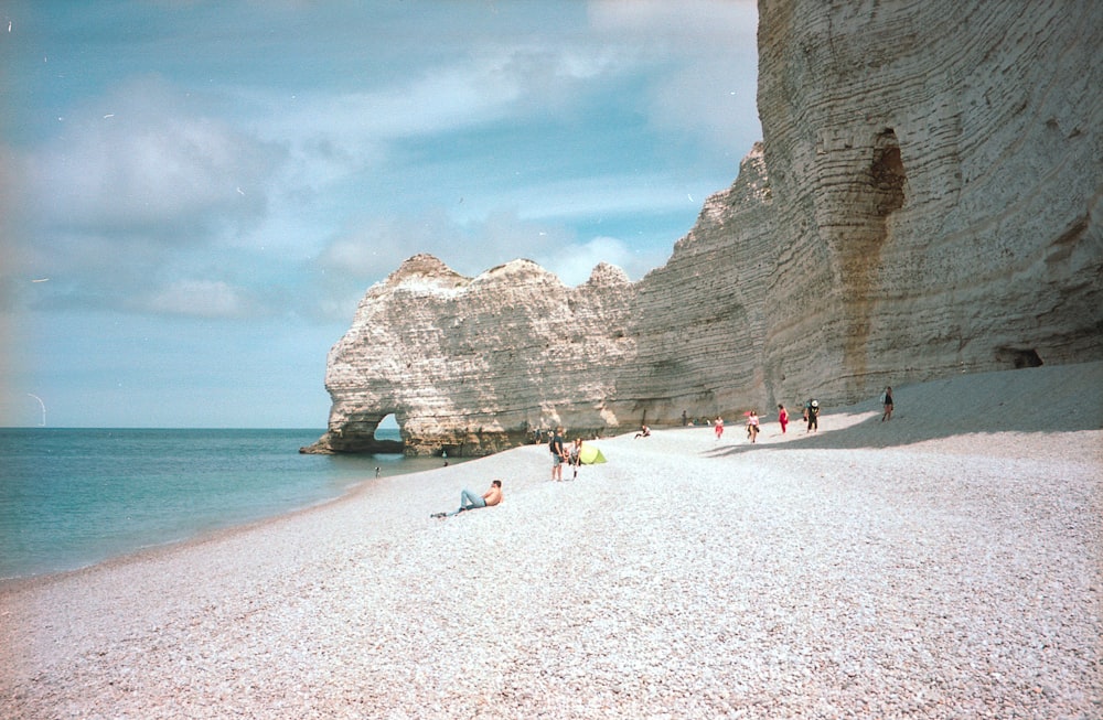 people on beach near rocky mountain during daytime