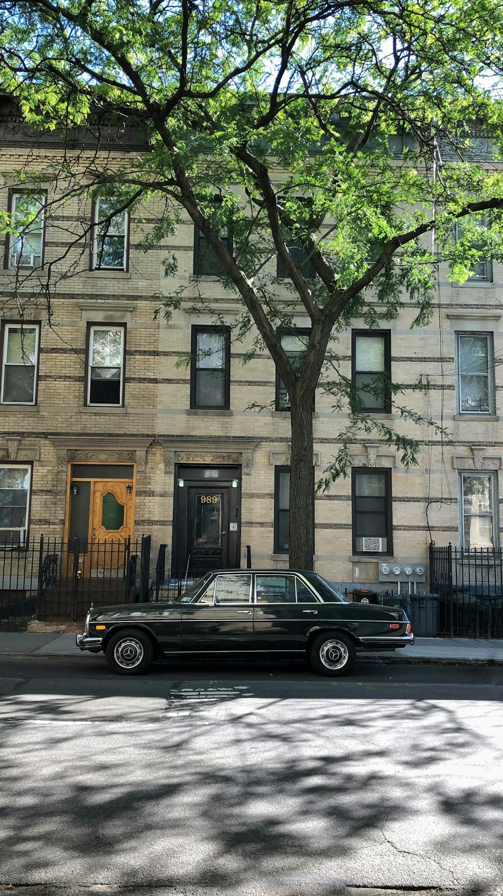 black sedan parked beside brown concrete building during daytime