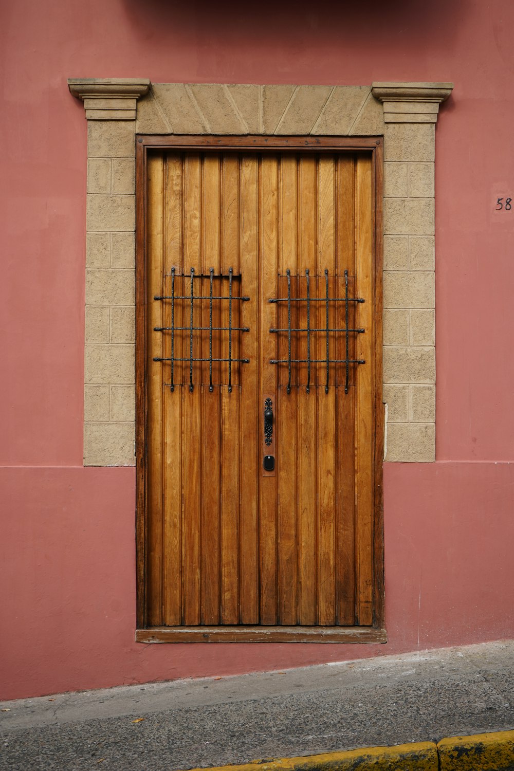 Puerta de madera marrón sobre pared de hormigón rosa