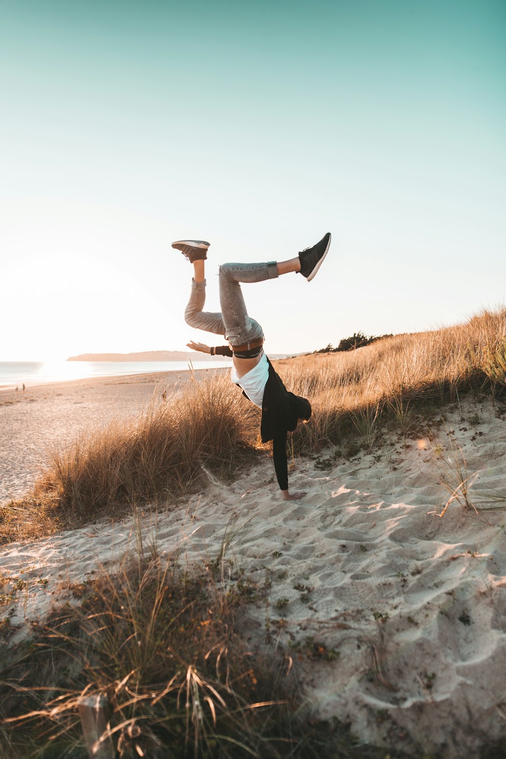 man in black pants and brown jacket jumping on gray rocky ground during daytime