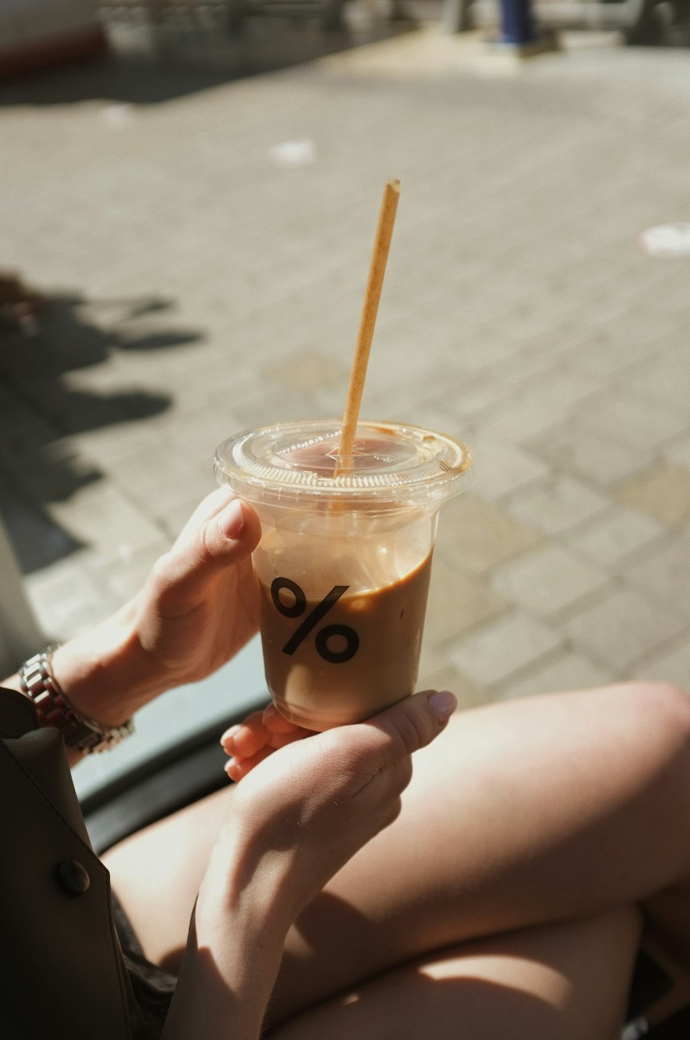 person holding clear plastic cup with brown liquid