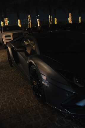 A sleek black luxury car parked under golden evening lights in Cannes.