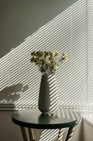 Morning light streaming through a window onto a vase filled with fresh garden blooms.