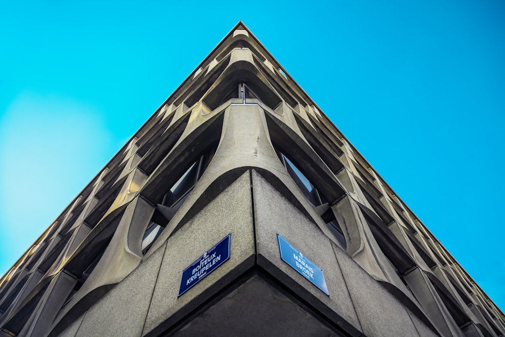 low angle photography of gray concrete building under blue sky during daytime