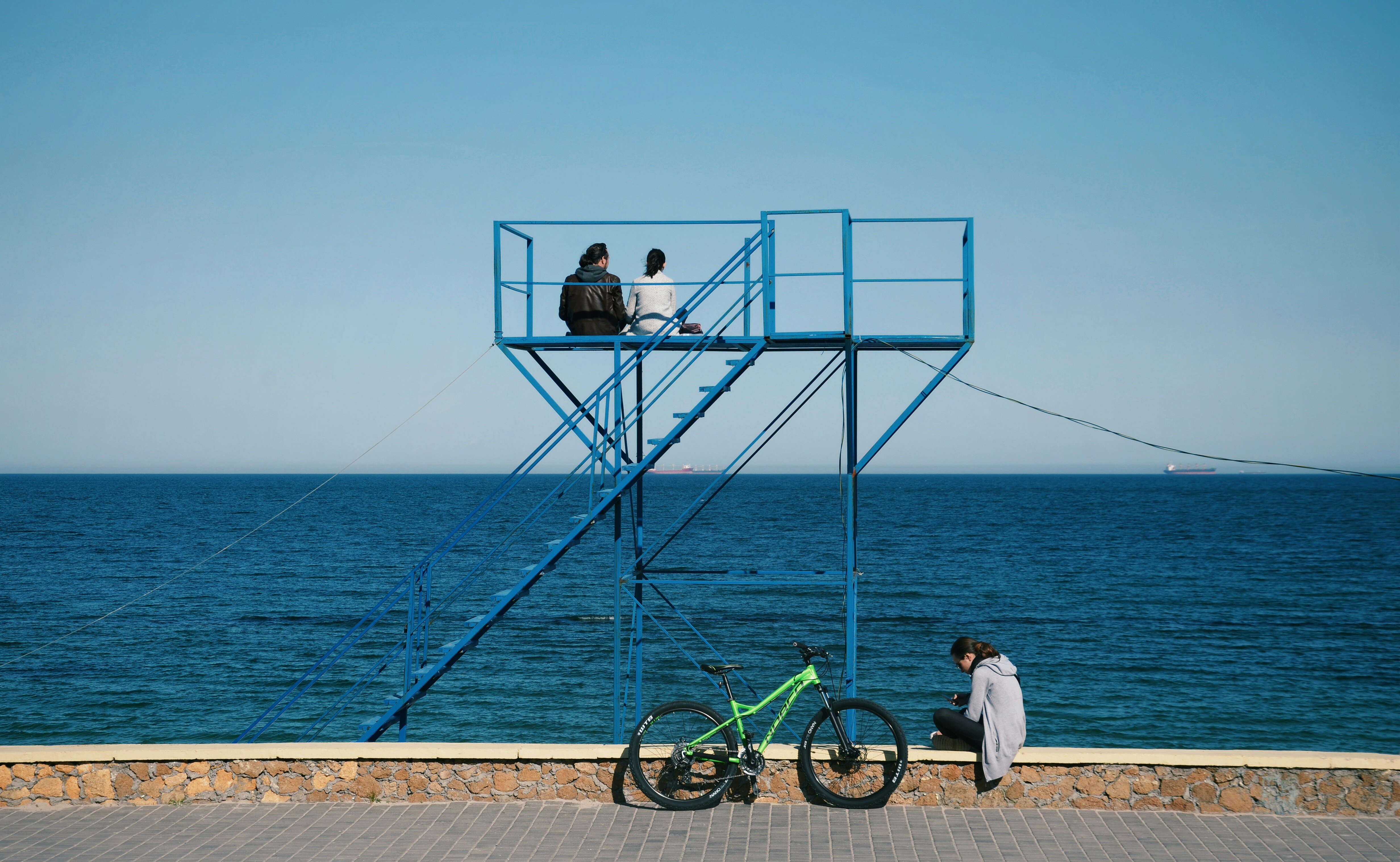 man in white shirt and black pants sitting on blue bicycle near body of water during