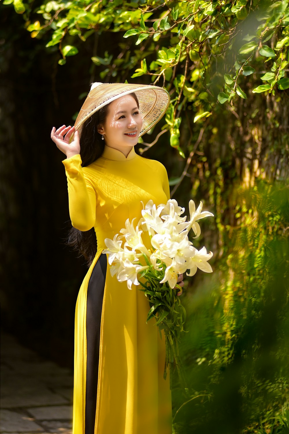 woman in yellow long sleeve dress wearing brown straw hat holding white flowers