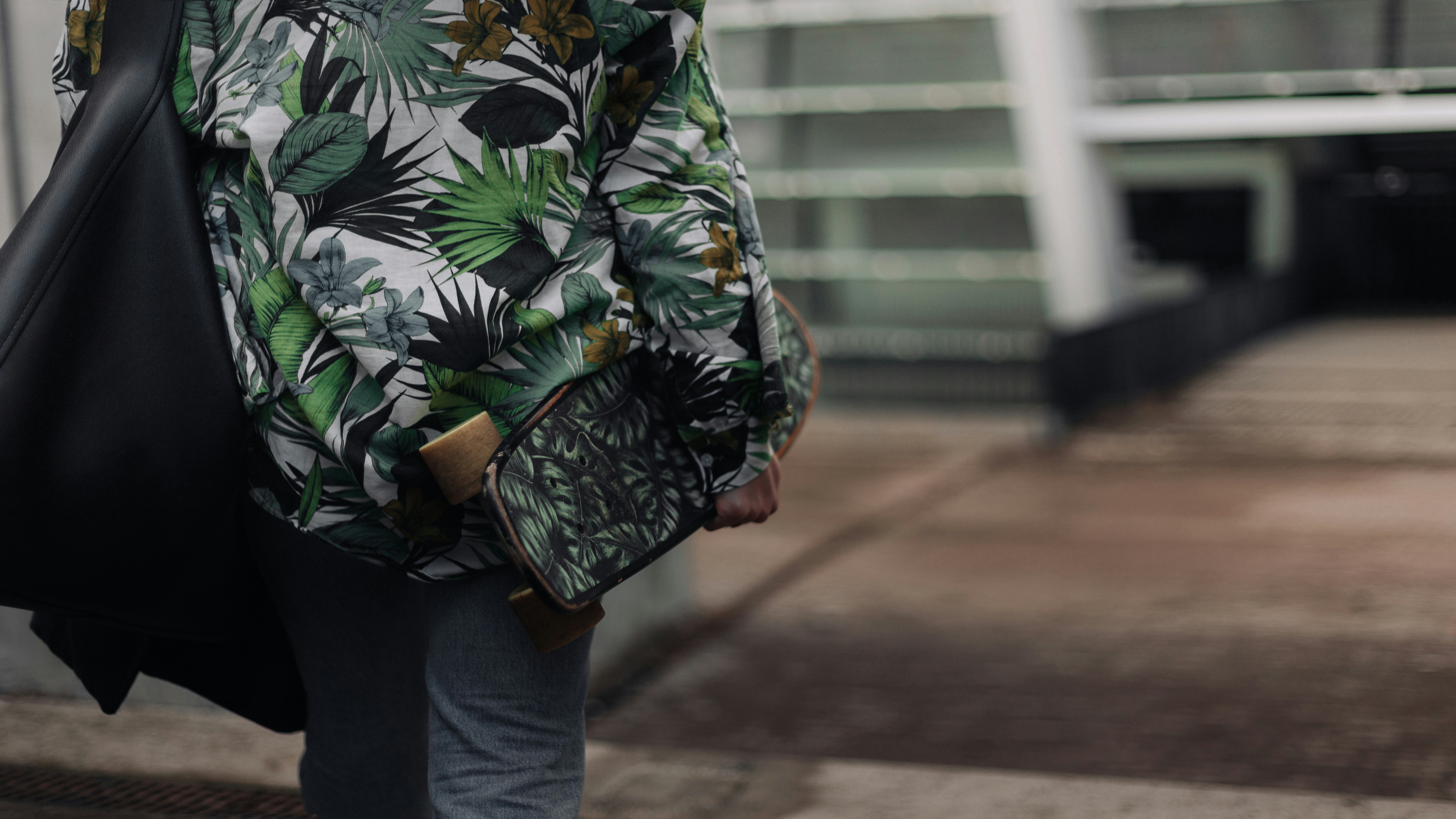 person in green white and black floral long sleeve shirt and blue denim jeans